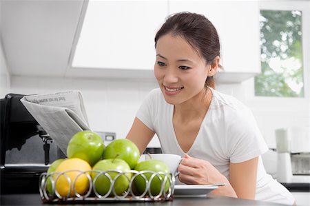 simsearch:625-02929083,k - Young woman reading a newspaper and drinking tea in a domestic kitchen Stock Photo - Premium Royalty-Free, Code: 625-02929121