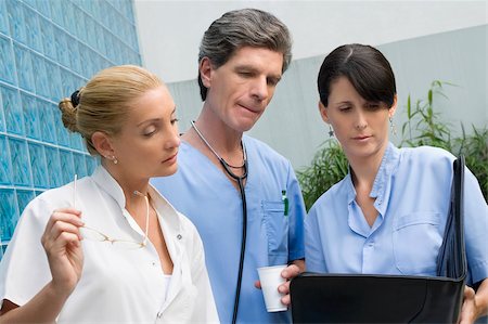 Two female surgeons and a male doctor discussing a medical report Stock Photo - Premium Royalty-Free, Code: 625-02929203