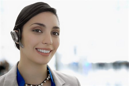 Portrait d'une femme d'affaires portant un dispositif libre de mains et souriant Photographie de stock - Premium Libres de Droits, Code: 625-02929468