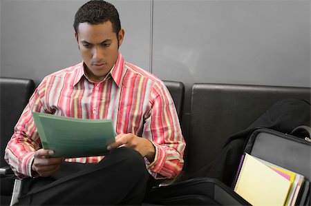 simsearch:625-02932602,k - Homme d'affaires de lecture d'un fichier dans la salle d'attente d'un aéroport Photographie de stock - Premium Libres de Droits, Code: 625-02929604