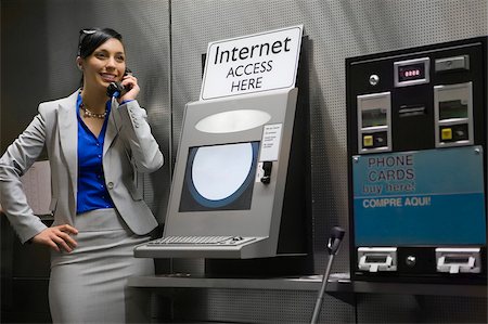 simsearch:625-02266955,k - Businesswoman talking on a pay phone at an airport and smiling Foto de stock - Royalty Free Premium, Número: 625-02929623