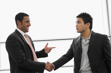 Two businessmen shaking hands at an airport Stock Photo - Premium Royalty-Free, Code: 625-02929644