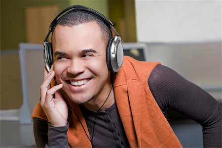 Close-up of a young man listening to music and smiling Stock Photo - Premium Royalty-Free, Code: 625-02929819