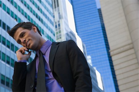 Low angle view of a businessman talking on a mobile phone and smiling Stock Photo - Premium Royalty-Free, Code: 625-02929876