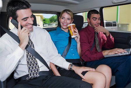 Close-up of a businesswoman sitting between two businessmen in a car and smiling Stock Photo - Premium Royalty-Free, Code: 625-02929981