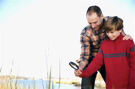 Low angle view of a mid adult man with his son holding a magnifying glass Stock Photo - Premium Royalty-Free, Code: 625-02930110