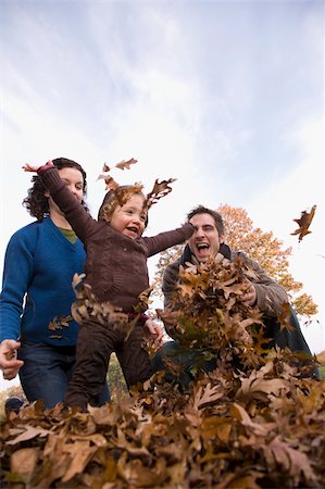 Low angle view of a family playing with leaves Stock Photo - Premium Royalty-Free, Code: 625-02930123