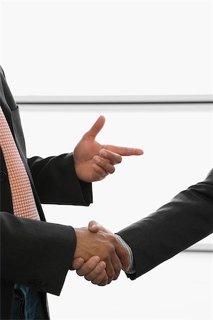 Close-up of two businessmen shaking hands at an airport Stock Photo - Premium Royalty-Free, Code: 625-02930176