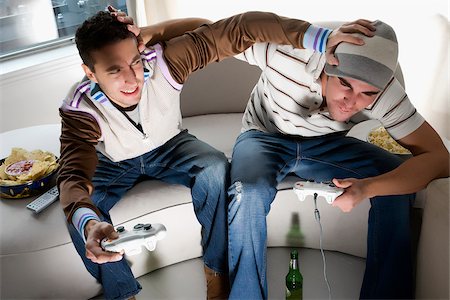 High angle view of two young men playing video game and rough housing Foto de stock - Sin royalties Premium, Código: 625-02930237