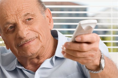 ethnic family watching tv - Close-up of a senior man operating a remote control Stock Photo - Premium Royalty-Free, Code: 625-02930268