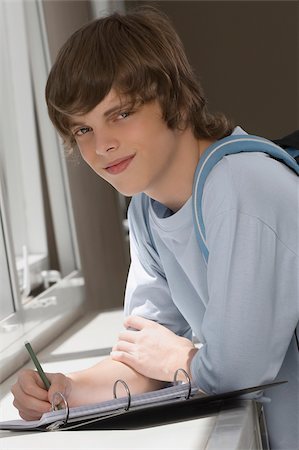 simsearch:625-02930319,k - Portrait of a teenage boy writing on spiral notebook and smiling Stock Photo - Premium Royalty-Free, Code: 625-02930319