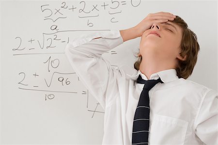 Close-up of a teenage boy standing in front of a whiteboard and looking stressed Stock Photo - Premium Royalty-Free, Code: 625-02930313