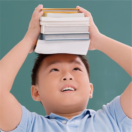Close-up of a schoolboy holding books on his head Stock Photo - Premium Royalty-Free, Code: 625-02930432