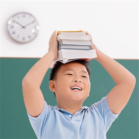 simsearch:625-01263529,k - Close-up of a schoolboy holding books on his head and smiling Foto de stock - Sin royalties Premium, Código: 625-02930452