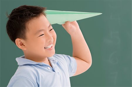 paper plane kid - Close-up of a schoolboy playing with a paper airplane Foto de stock - Sin royalties Premium, Código: 625-02930471