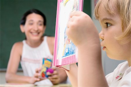 Close-up of a boy reading a book with his teacher sitting beside him Foto de stock - Sin royalties Premium, Código: 625-02930496