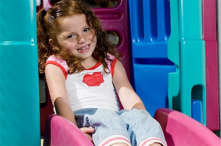 simsearch:693-06967402,k - Portrait d'une jeune fille assise sur une diapositive et souriant Photographie de stock - Premium Libres de Droits, Code: 625-02930506