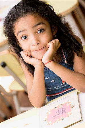 Portrait d'une jeune fille assise à un bureau avec ses mains sur son menton Photographie de stock - Premium Libres de Droits, Code: 625-02930549