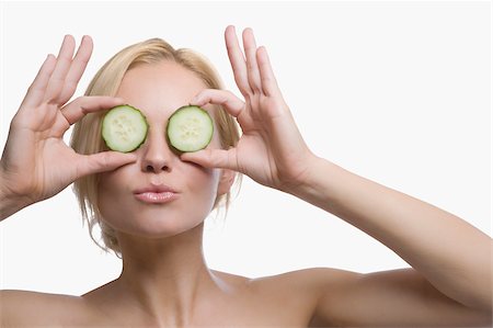 Close-up of a young woman holding cucumber slices in front of her eyes Stock Photo - Premium Royalty-Free, Code: 625-02930726
