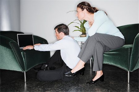 Businessman using a laptop with a businesswoman sitting behind him Stock Photo - Premium Royalty-Free, Code: 625-02930751