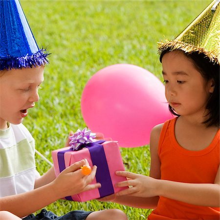 Close-up of a boy giving a birthday present to a girl Stock Photo - Premium Royalty-Free, Code: 625-02930865