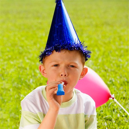 party blowers blown - Portrait of a boy blowing a party horn blower Stock Photo - Premium Royalty-Free, Code: 625-02930862