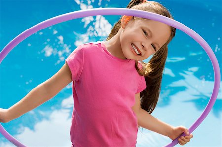 Portrait of a girl holding a plastic hoop and smiling Stock Photo - Premium Royalty-Free, Code: 625-02930872
