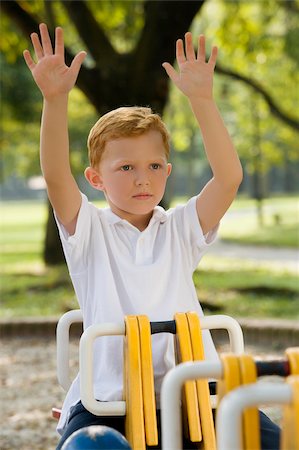 Boy sitting on a ride with his arms raised in a park Stock Photo - Premium Royalty-Free, Code: 625-02930907