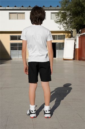 Rear view of a schoolboy standing in front of a school building Stock Photo - Premium Royalty-Free, Code: 625-02930969