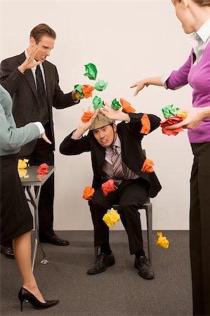 failure - Businessman protecting himself from colleagues throwing paper balls Stock Photo - Premium Royalty-Free, Code: 625-02931259