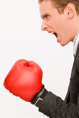 política en la oficina - Side profile of a businessman wearing boxing gloves Foto de stock - Sin royalties Premium, Código: 625-02931277