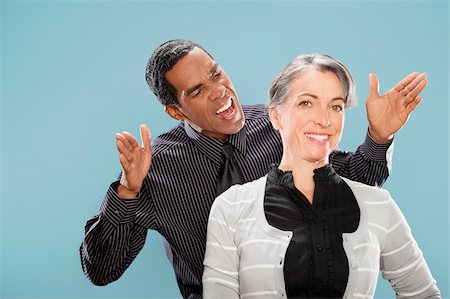 furioso - Portrait of a businesswoman smiling with a businessman shouting at her Stock Photo - Premium Royalty-Free, Code: 625-02931322