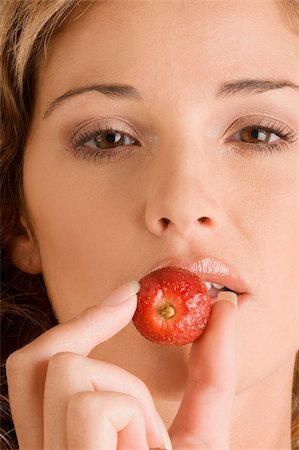 simsearch:693-06021794,k - Portrait of a young woman eating a strawberry Stock Photo - Premium Royalty-Free, Code: 625-02931478