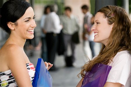 Close-up of two young women looking at each other and smiling Stock Photo - Premium Royalty-Free, Code: 625-02931674
