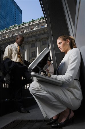 person opening shirt - Low angle view of a businesswoman looking into a briefcase with two businessmen standing in the background Stock Photo - Premium Royalty-Free, Code: 625-02931809