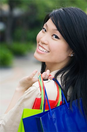 simsearch:625-02266826,k - Portrait d'une jeune femme transportant des sacs à provisions et souriant Photographie de stock - Premium Libres de Droits, Code: 625-02931929