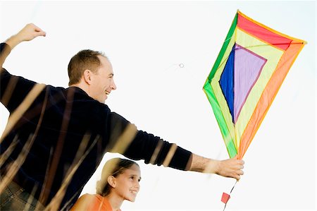 people flying kites in the sky - Rear view of a mid adult man with his daughter flying a kite Stock Photo - Premium Royalty-Free, Code: 625-02931937