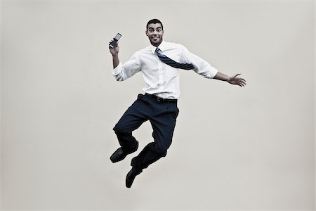Portrait of a businessman holding a mobile phone and jumping Stock Photo - Premium Royalty-Free, Code: 625-02931991