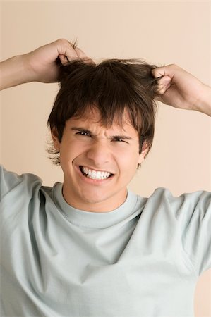 simsearch:625-02933107,k - Portrait of a young man pulling his hair Foto de stock - Royalty Free Premium, Número: 625-02932040