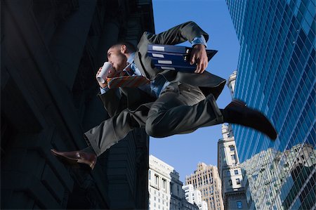 simsearch:625-02929949,k - Low angle view of a businessman jumping in mid-air and drinking Foto de stock - Sin royalties Premium, Código: 625-02932102