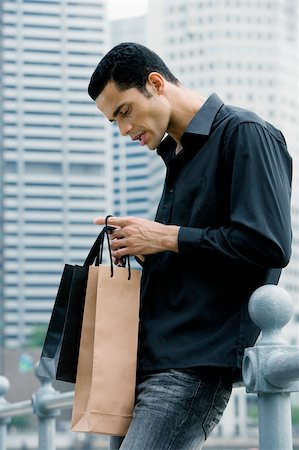 Side profile of a mid adult man looking into shopping bags Stock Photo - Premium Royalty-Free, Code: 625-02932121