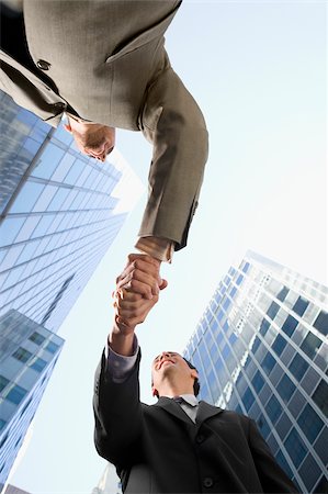 Low angle view of two businessmen shaking hands and smiling Stock Photo - Premium Royalty-Free, Code: 625-02932235