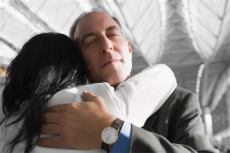 people hugging at airport - Close-up of a businessman and a businesswoman hugging each other at an airport Stock Photo - Premium Royalty-Free, Code: 625-02932303