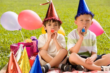 Two boys sitting together and blowing party horns Stock Photo - Premium Royalty-Free, Code: 625-02932368