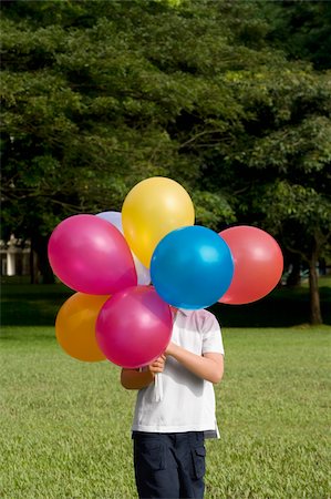 simsearch:649-06623087,k - Boy holding balloons in a park Foto de stock - Royalty Free Premium, Número: 625-02932411