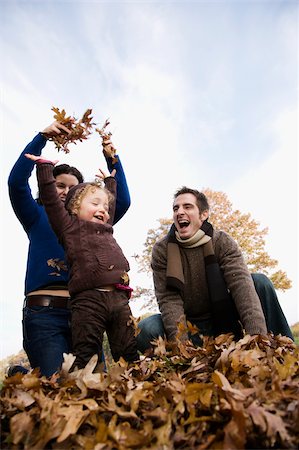 Low angle view of a couple and their daughter playing with leaves Foto de stock - Sin royalties Premium, Código: 625-02932421