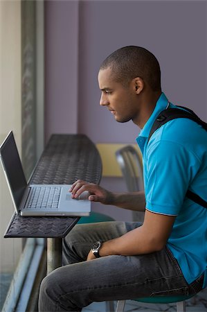 shaved head profile asian - Side profile of a young man using a laptop in a cafe Stock Photo - Premium Royalty-Free, Code: 625-02932547
