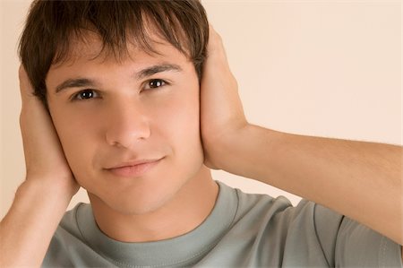 Portrait of a young man covering his ears with his hands Stock Photo - Premium Royalty-Free, Code: 625-02932778