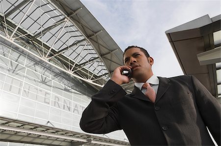simsearch:625-02932602,k - Faible angle vue d'un homme d'affaires parlant sur un téléphone mobile en dehors d'un aérodrome Photographie de stock - Premium Libres de Droits, Code: 625-02932795