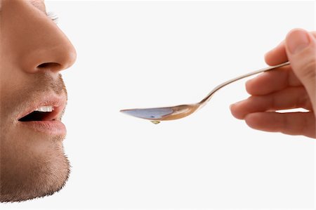 spoon with syrup - Mid adult man holding a spoon and taking medicine Stock Photo - Premium Royalty-Free, Code: 625-02932810